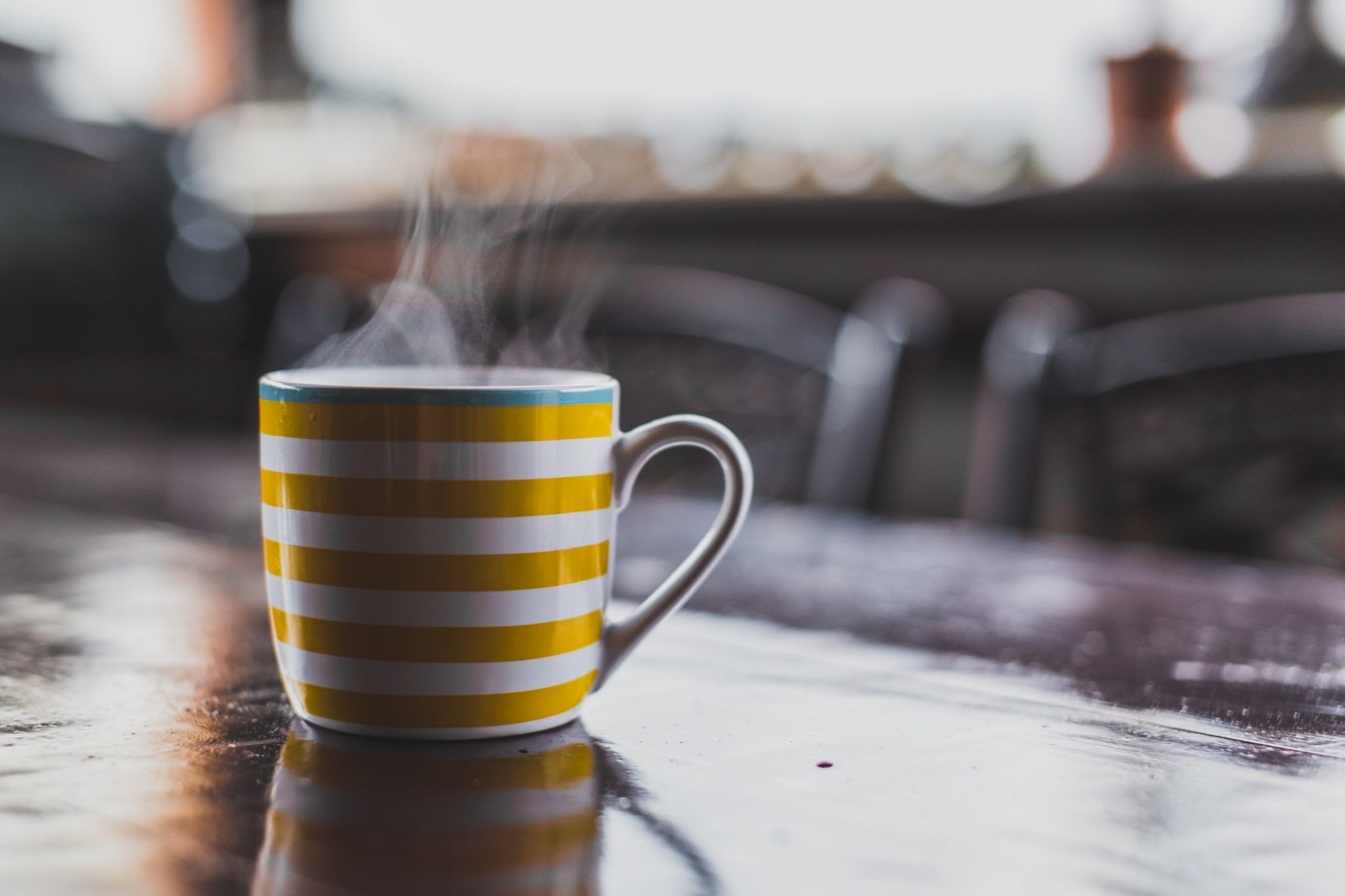 Hot coffee in a stripped yellow mug